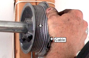 Tighten garage door cable on drum.