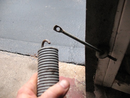 How are garage door tension springs adjusted?