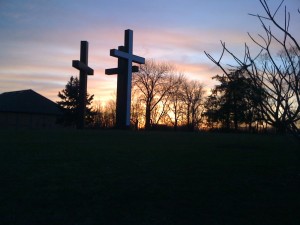 A view of three crosses with a sunset behind them, indicating the preferred order.  
