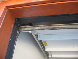 A view of an installed black top and side weatherstripping seal on an oak-looking garage door. 