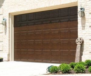 An image of a brown panel garage door on a brick house.