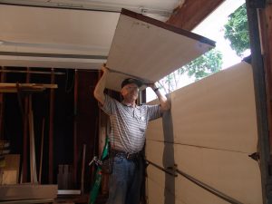 Dan Musick holding a garage door section over his head. 