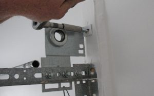 A person shown securing the top of an anchor bracket with a lag screw on a 15-inch radius track.