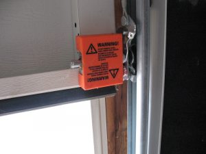 A red cover over a spring-loaded arm on a Hormann garage door.