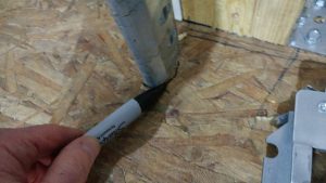 A person using a permanent marker to mark where the bottom of the  track meets the floor.