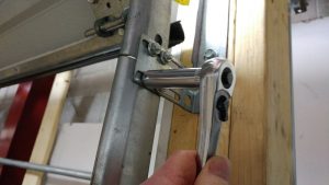 A person using a ratchet is removing two nuts from a flag bracket.