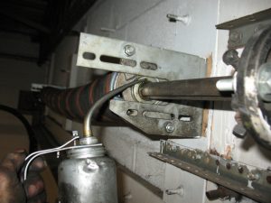 A garage door professional lubricating the bearings on an overhead garage door using an oil can.