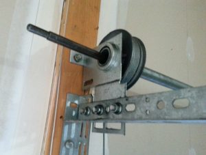 A view of the cable drum, end bearing plate, and horizontal track on a garage door.