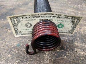 A one-dollar bill placed in between the gaps of a self-storage garage door spring.