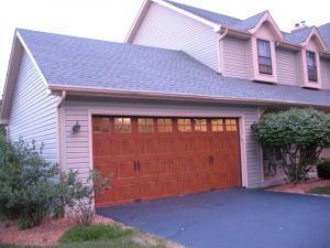 A house with double wooden carriage house garage doors with windows in the top panel. 