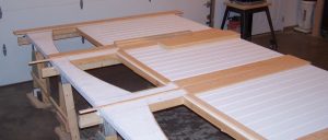 White custom garage doors laying on sawhorses awaiting assembly.