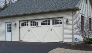 An almond colored house with custom garage doors containing windows.