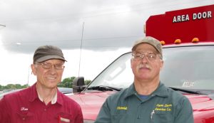 Picture of Harold Poling (on the right ) and Dan Musick (on the left) in front of an "Area Door Service Co." red truck.