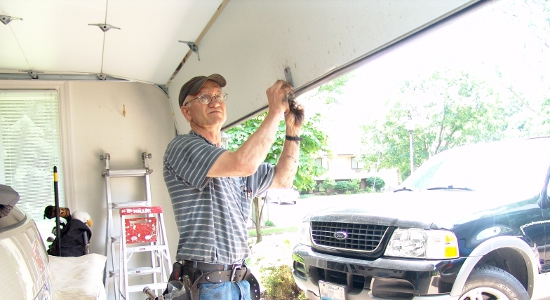 A Garage Door Service Professional standing with the garage door opened and looking at the door to diagnose the issue.