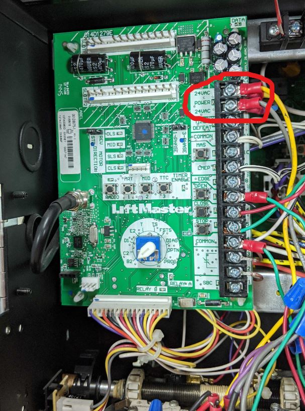 A LiftMaster Logic 5 control board with the top two screws circled in red indicating 24 volt connections.  