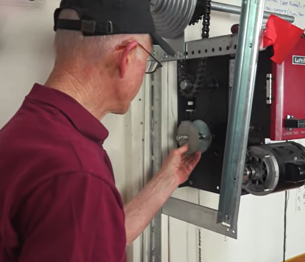 A clutch plate being reinstalled on the shaft of a commercial LiftMaster operator, with the pressure plate behind it